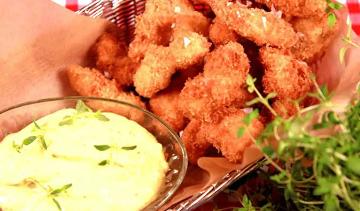 Korg med gyllene chicken nuggets, serverade med en krämig dipp och färska örter.