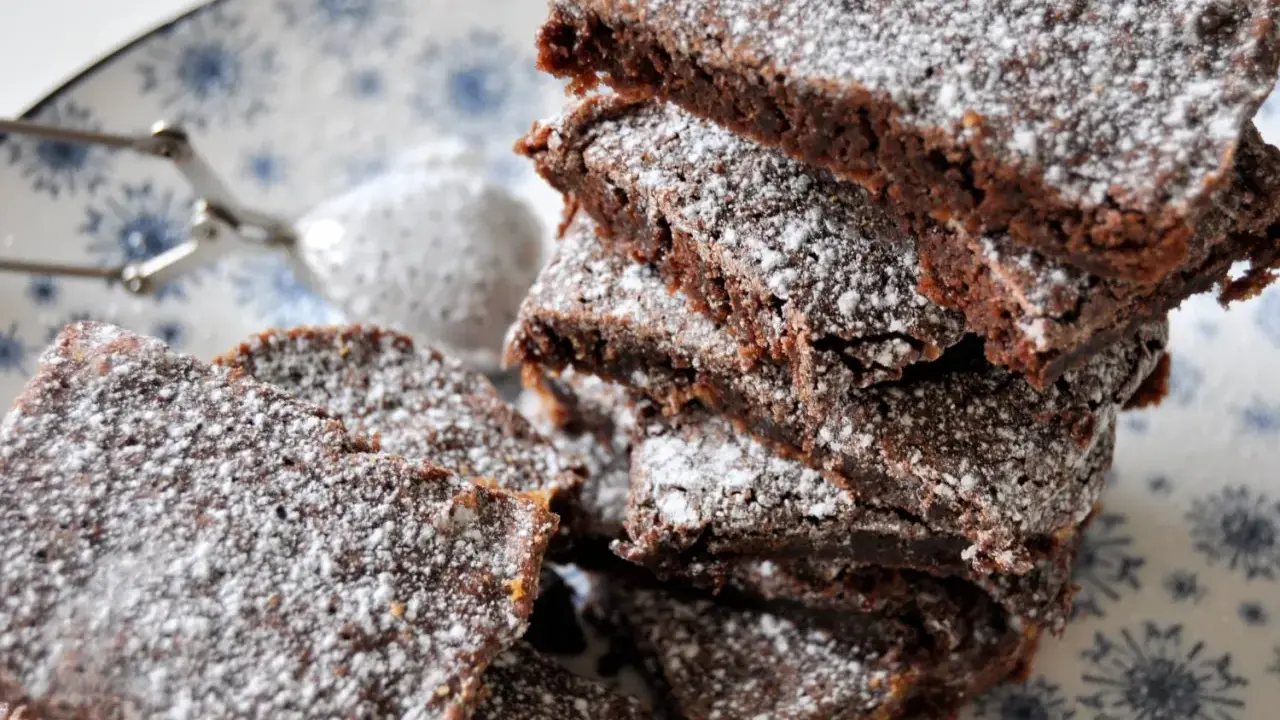 En hög med saftig kladdkaka i långpanna, pudrad med florsocker. Perfekt för fikat!