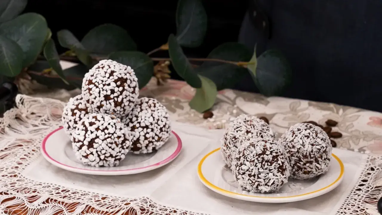 Fredriks fika: de godaste chokladbollar, rullade i kokos och pärlsocker, serverade på små fat med en grönskande bakgrund.