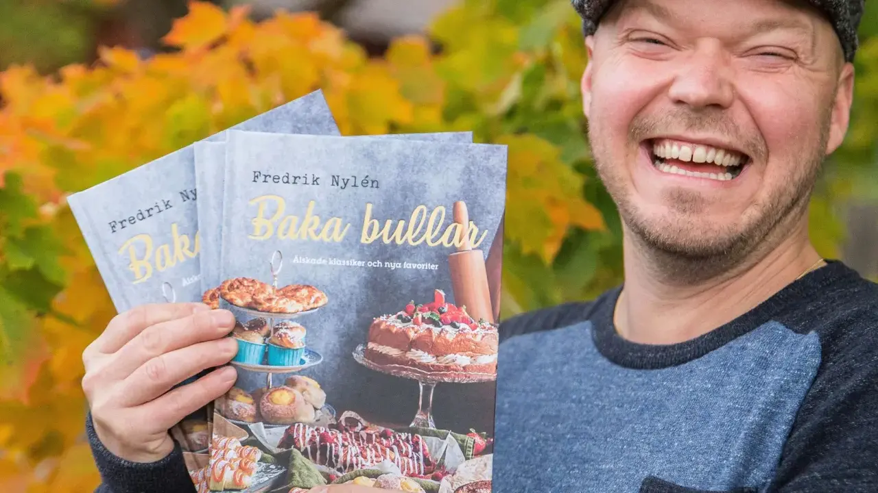Fredrik Nylen håller upp sina böcker om kanelbullar med kardemumma, perfekt för Fredriks fika.