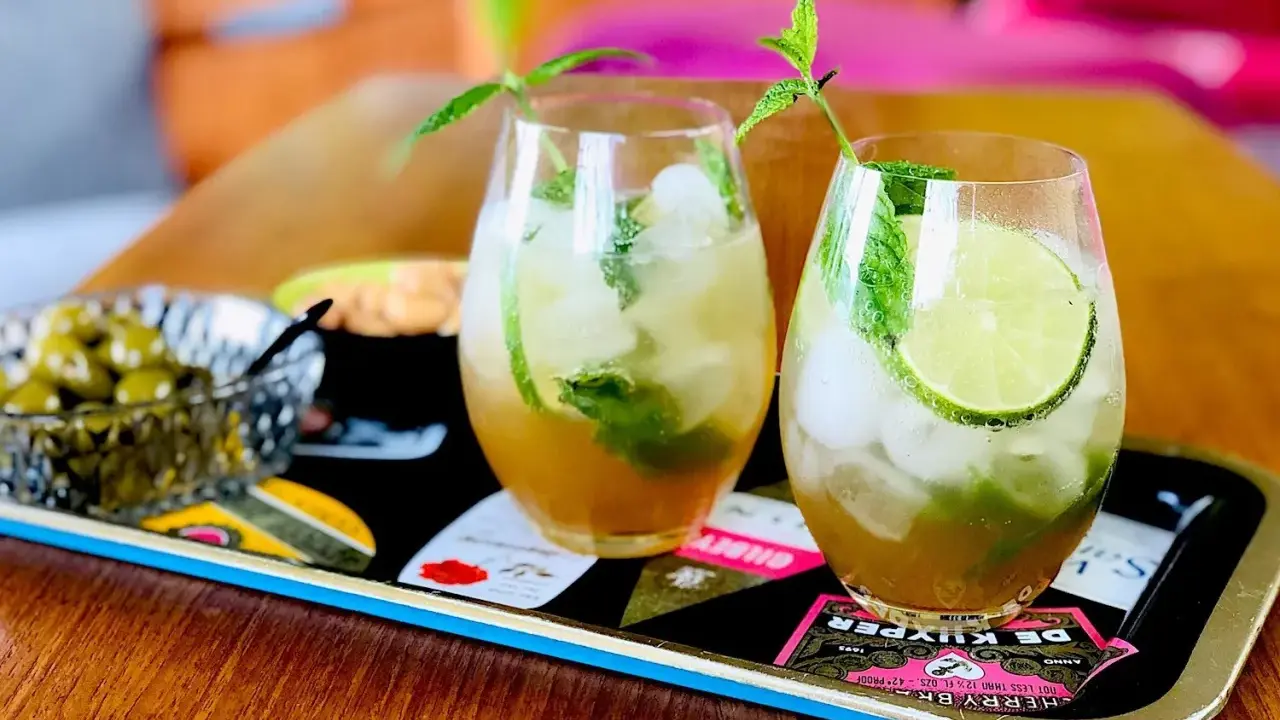 Två uppfriskande mojitos med mynta och lime, perfekt för ett somrigt mojito recept. Serveras med oliver på ett dekorativt fat.
