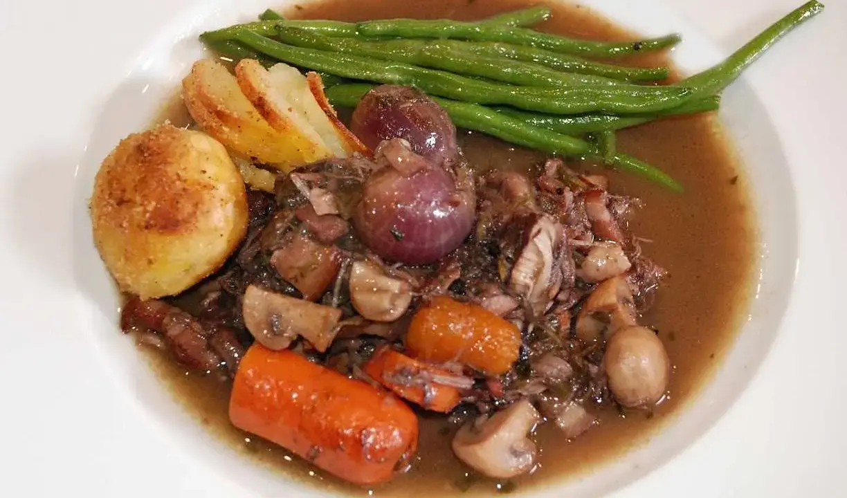 En portion coq au vin med potatis, haricots verts och champinjoner. En klassisk fransk rätt som doftar underbart.