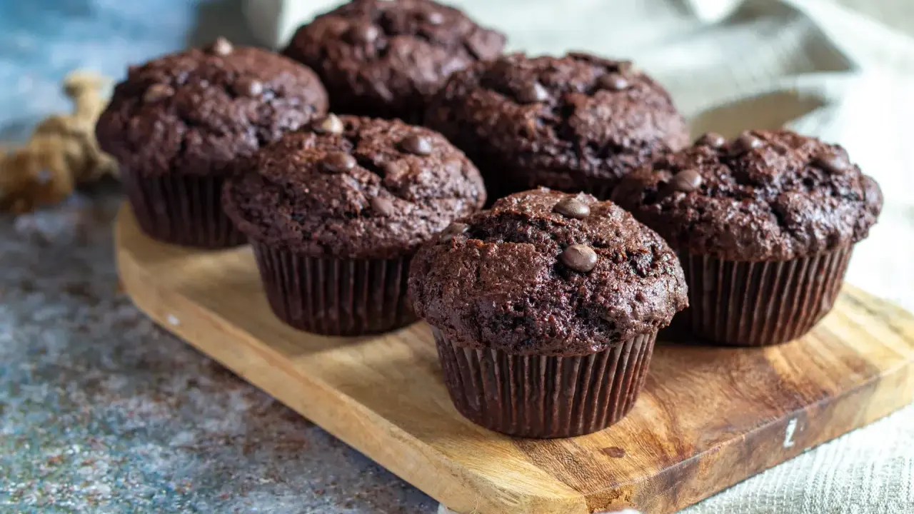 Fluffiga muffins recept: Mörka chokladmuffins med chokladknappar på en träbricka. Perfekta för fikat!