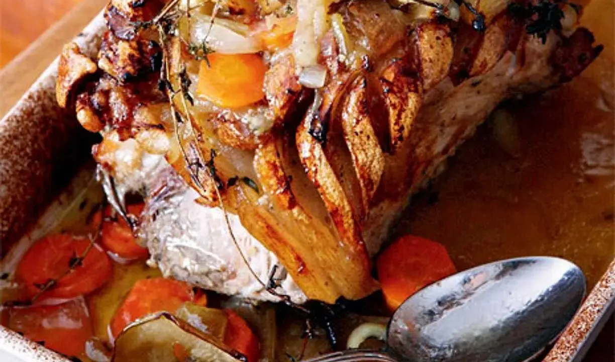 En saftig skinkstek med knaprig svål, serverad med rotfrukter och en sked redo att ösa. Ett perfekt skinkstek recept för helgen.