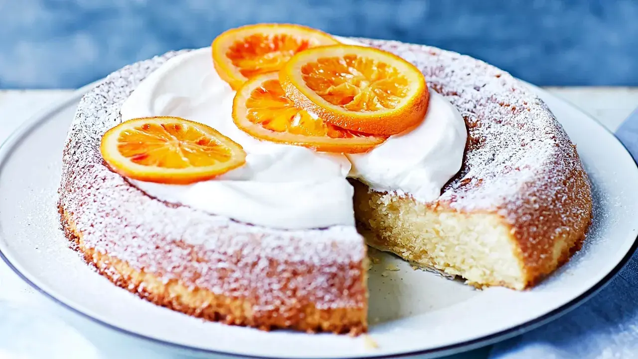 En saftig citron och mandelkaka, pudrad med florsocker och toppad med vispgrädde och apelsinskivor. Perfekt för Fredriks fika!