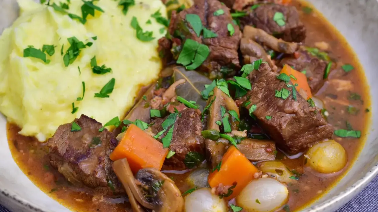En mustig boeuf bourguignon med möra köttbitar, champinjoner, morötter och små lökar, serverad med krämigt potatismos.