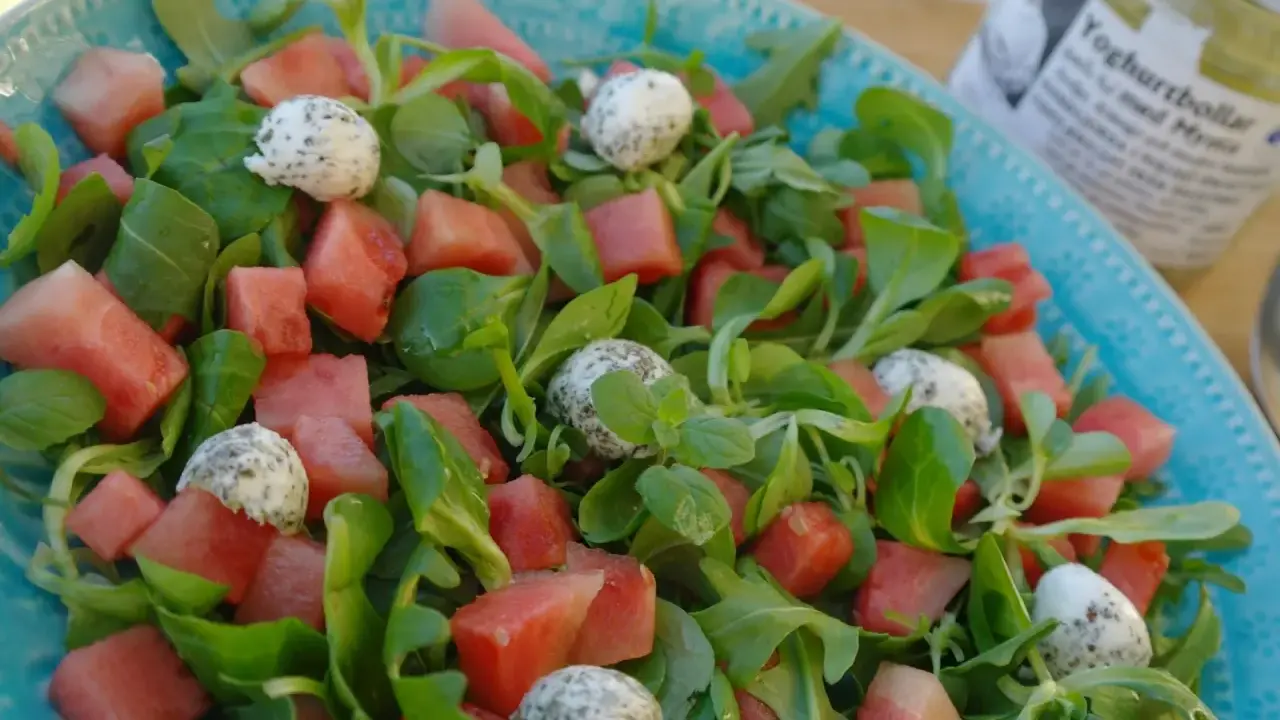 En uppfriskande sallad med vattenmelon, gröna blad och små bollar av ost, perfekt som sallad till paj.