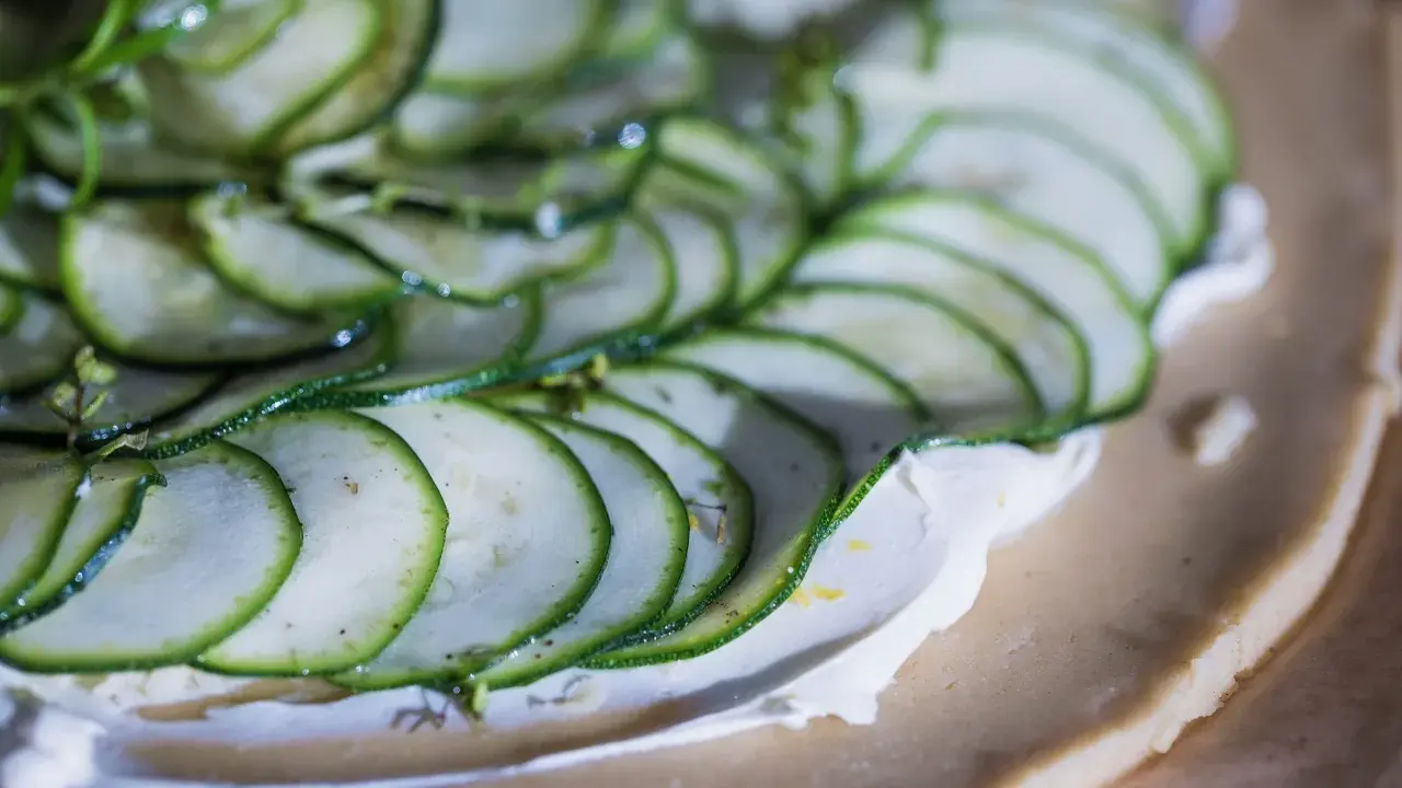 Tunna skivor av zucchini läggs på en krämig fyllning på en pajdeg. En underbart god paj som snart är redo att avnjutas.