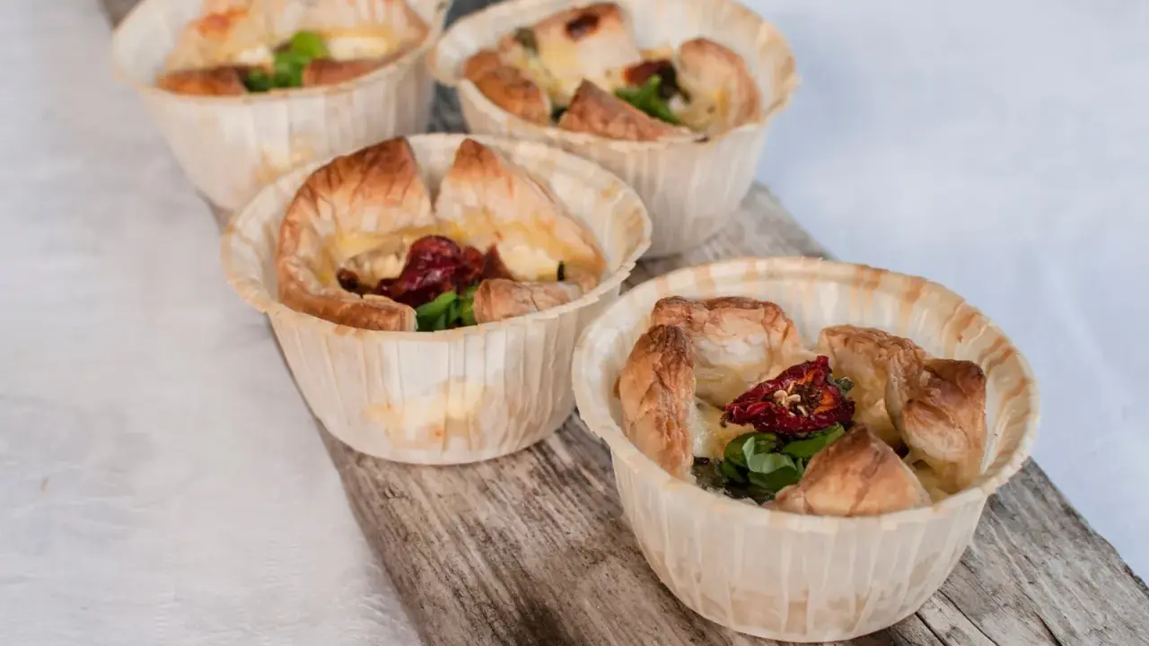 Fyra små, gyllene minipajer i muffinsform, fyllda med ost, soltorkade tomater och grönt. Perfekta som tilltugg.