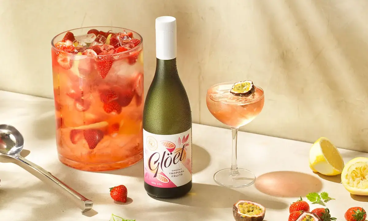 En flaska vitt vin står bredvid en drink med passionsfrukt och jordgubbar. Perfekt för att drink vitt vin en solig dag.