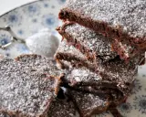 En hög med saftig kladdkaka i långpanna, pudrad med florsocker. Perfekt för fikat!