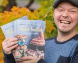 Fredrik Nylen håller upp sina böcker om kanelbullar med kardemumma, perfekt för Fredriks fika.