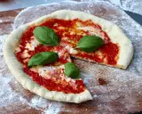 En nybakad pizza på grillen, med tomatsås, mozzarella och färsk basilika, redo att avnjutas.