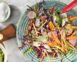 En fräsch asiatisk kålsallad med strimlad morot, rödkål, gurka och rädisor, toppad med sesamfrön.