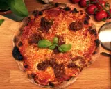 En härlig napolitansk pizza med köttfärs och basilika, redo att skäras med pizzaskäraren.