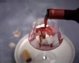 En flaska häller upp rött dessertvin till glass i ett glas. En perfekt kombination för en lyxig efterrätt.