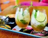 Två uppfriskande mojitos med mynta och lime, perfekt för ett somrigt mojito recept. Serveras med oliver på ett dekorativt fat.