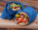 Två kebabrullar inslagna i jeans på en träbricka. Ett enkelt kebab recept med färska grönsaker.