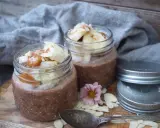 Två burkar med choklad overnight oats, toppade med banan, mandelflagor och en sked. Perfekt för en snabb frukost.