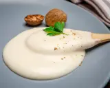 Krämig bechamelsås på en tallrik med muskotnötter och persilja. Perfekt för ditt bechamelsås recept.