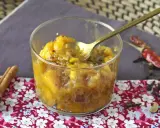 En skål med gyllene mango chutney, perfekt för ditt mango chutney recept. Kryddor som kanel och chili ligger bredvid.