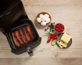 Krispigt bacon i airfryer, redo för en god frukost med ägg, bär och ost.