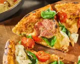 Fredriks fika: Krispig pizzadeg med salami, tomater och färsk basilika på en träskärbräda.