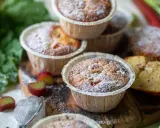Fredriks fika: fluffiga rabarbermuffins pudrade med florsocker, med färsk rabarber och gröna blad i bakgrunden.
