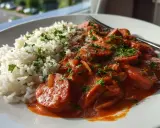 En tallrik med fluffigt ris och en krämig korv stroganoff, toppad med persilja. Perfekt för en god middag!