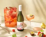 En flaska vitt vin står bredvid en drink med passionsfrukt och jordgubbar. Perfekt för att drink vitt vin en solig dag.