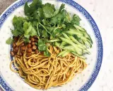 En läcker asiatisk nudelsallad med krispig gurka, rostade jordnötter och färsk koriander på en vackert mönstrad tallrik.