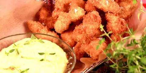 Korg med gyllene chicken nuggets, serverade med en krämig dipp och färska örter.