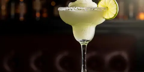 En frostig frozen margarita med saltkant och limeklyfta, perfekt för en varm sommardag.
