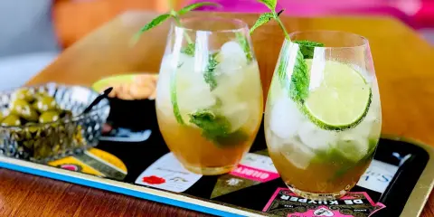 Två uppfriskande mojitos med mynta och lime, perfekt för ett somrigt mojito recept. Serveras med oliver på ett dekorativt fat.