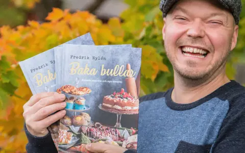 Fredrik Nylen håller upp sina böcker om kanelbullar med kardemumma, perfekt för Fredriks fika.