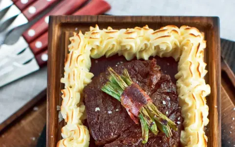 En saftig biff med sparris inslagen i bacon, omgiven av krispig potatispuré. Ett perfekt plankstek recept för en festmåltid.