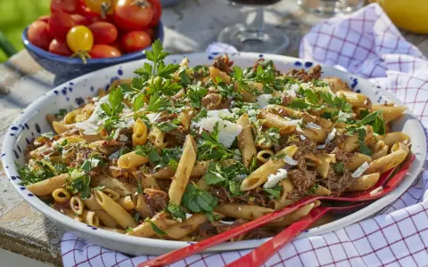 Stor skål med penne pasta och köttfärssås, toppad med persilja och parmesan. Perfekt för varm mat till många.