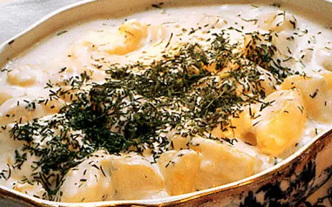 En krämig stuvad potatis med dill, serverad i ett vackert uppläggningsfat.