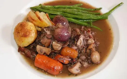 En portion coq au vin med potatis, haricots verts och champinjoner. En klassisk fransk rätt som doftar underbart.