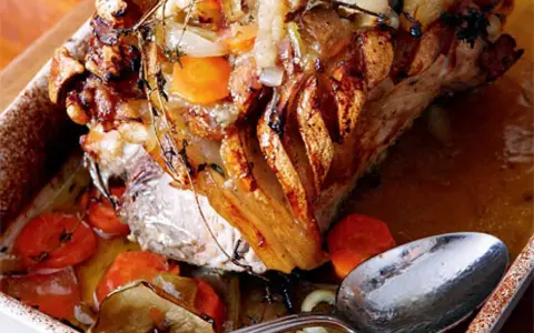 En saftig skinkstek med knaprig svål, serverad med rotfrukter och en sked redo att ösa. Ett perfekt skinkstek recept för helgen.