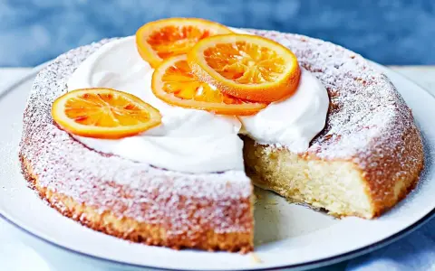 En saftig citron och mandelkaka, pudrad med florsocker och toppad med vispgrädde och apelsinskivor. Perfekt för Fredriks fika!