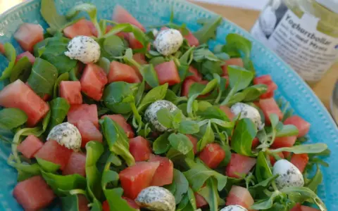 En uppfriskande sallad med vattenmelon, gröna blad och små bollar av ost, perfekt som sallad till paj.