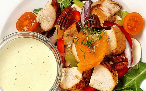 En härlig kycklingsallad med saftiga kycklingbitar, nötter, apelsin och en krämig dressing till kycklingsallad.