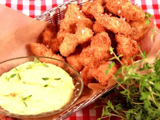 Korg med gyllene chicken nuggets, serverade med en krämig dipp och färska örter.