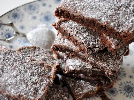 En hög med saftig kladdkaka i långpanna, pudrad med florsocker. Perfekt för fikat!