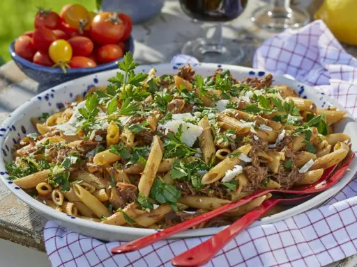 Stor skål med penne pasta och köttfärssås, toppad med persilja och parmesan. Perfekt för varm mat till många.