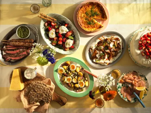 En lyxig sallad till buffé med bär och grädde, flankerad av grillspett, quiche och rökt lax.