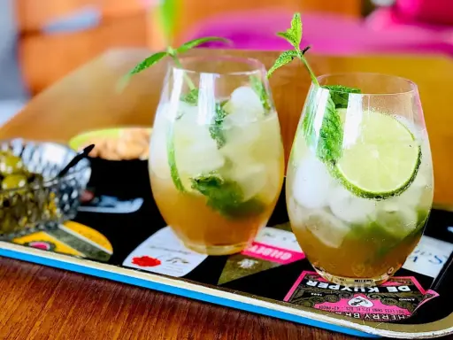 Två uppfriskande mojitos med mynta och lime, perfekt för ett somrigt mojito recept. Serveras med oliver på ett dekorativt fat.