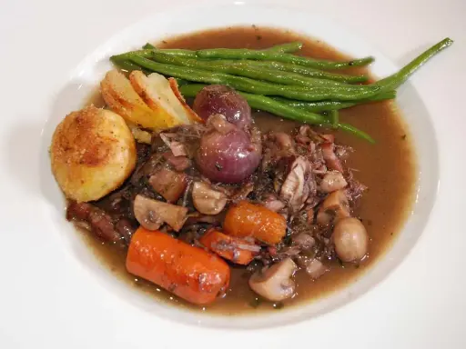 En portion coq au vin med potatis, haricots verts och champinjoner. En klassisk fransk rätt som doftar underbart.
