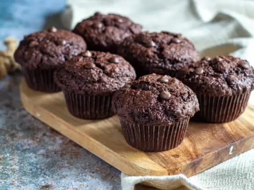 Fluffiga muffins recept: Mörka chokladmuffins med chokladknappar på en träbricka. Perfekta för fikat!